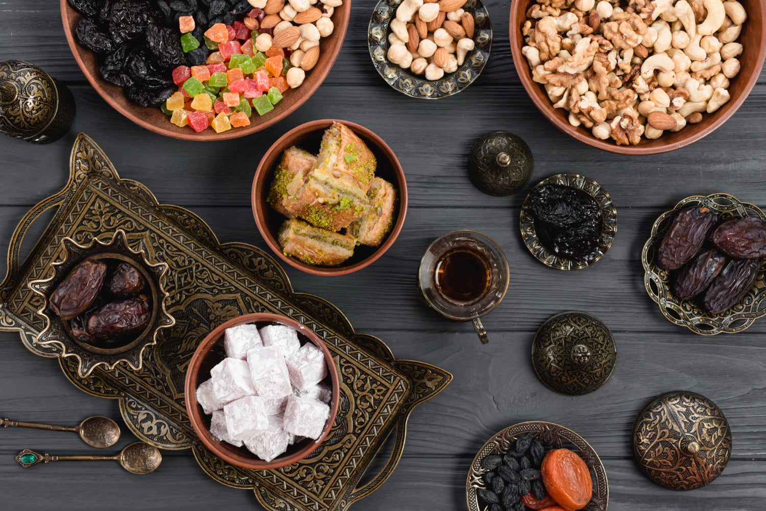 Assorted dried fruits, nuts, and sweets on a wooden table with decorative elements.