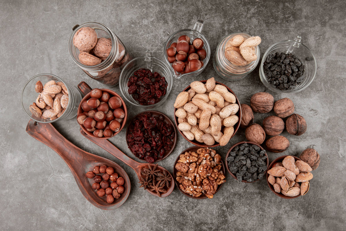 Assorted nuts and dried fruits in glass containers on a gray surface
